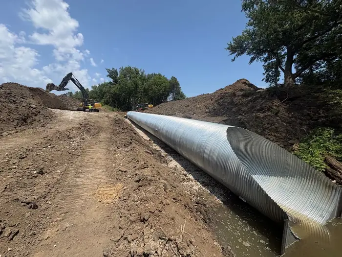 Large corrugated metal culvert run bedded in a trench