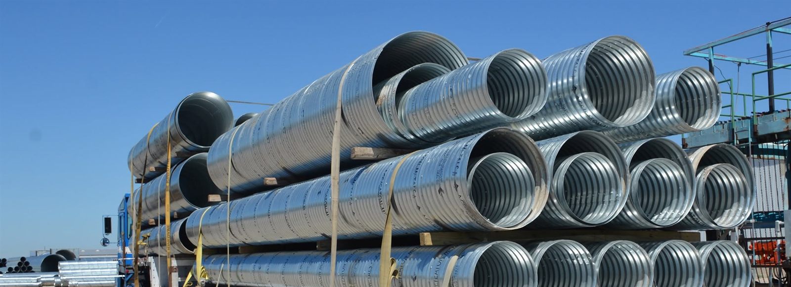Flatbed load of galvanized corrugated metal culvert pipe in several diameters, strapped and blocked for transport